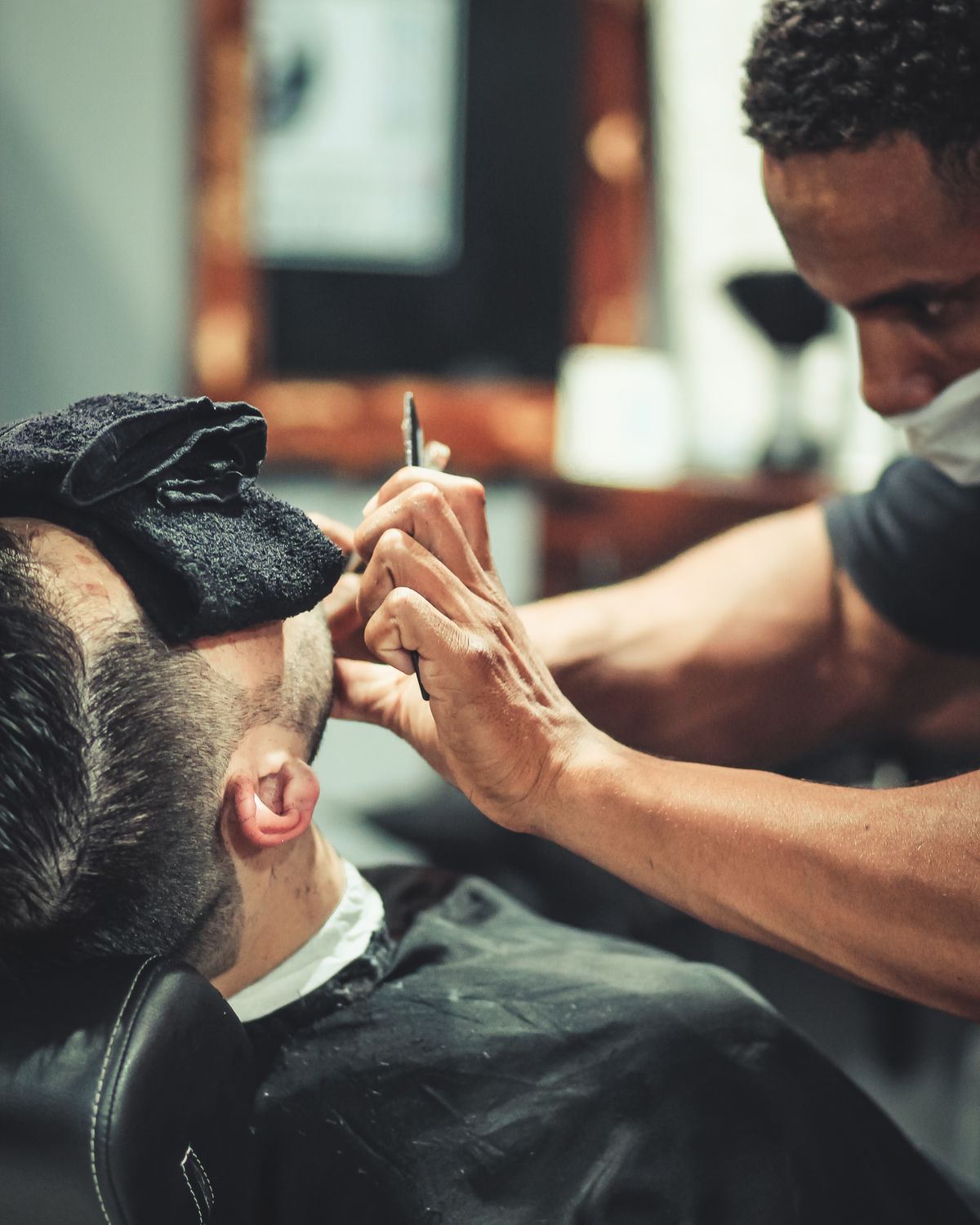 Barber trimming a client's beard with a straight razor